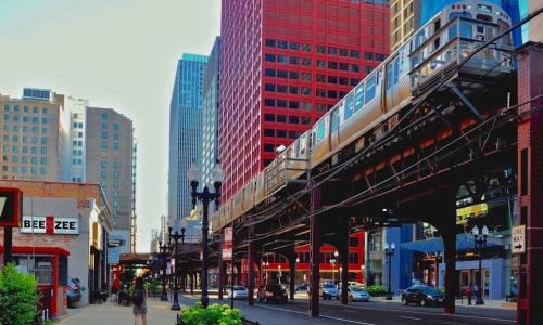 Chicago L train on elevated tracks with city skyline - chicago apartments near transit